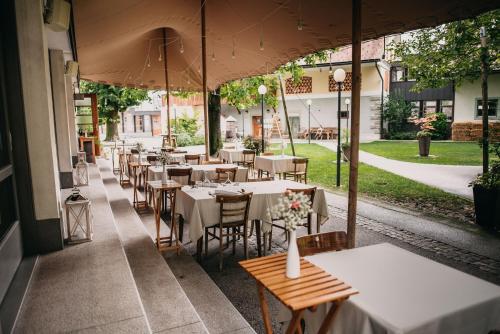 um restaurante com mesas e cadeiras e um guarda-sol em Hotel Dvor Jezersek Brnik em Cerklje na Gorenjskem