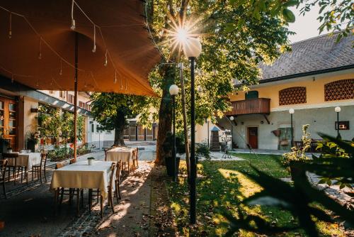 um pátio exterior com mesas e um guarda-chuva em Hotel Dvor Jezersek Brnik em Cerklje na Gorenjskem