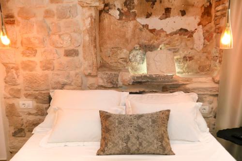 a bedroom with a white bed with a stone wall at Villa Teuta in Trogir