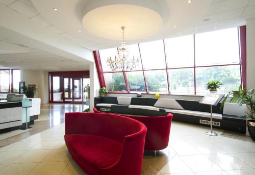 una sala de espera con sillas rojas y ventanas en Grand Hotel Admiral Palace, en Chianciano Terme