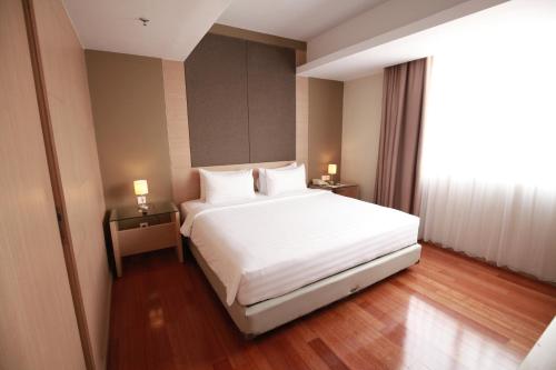 1 dormitorio con cama blanca y ventana grande en Swiss-Belinn Airport Jakarta, en Tangerang