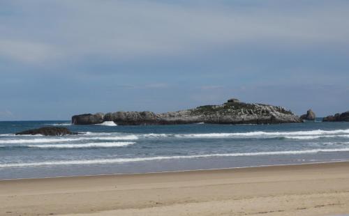 uma praia com uma ilha na água em Hotel Los Juncos em Noja