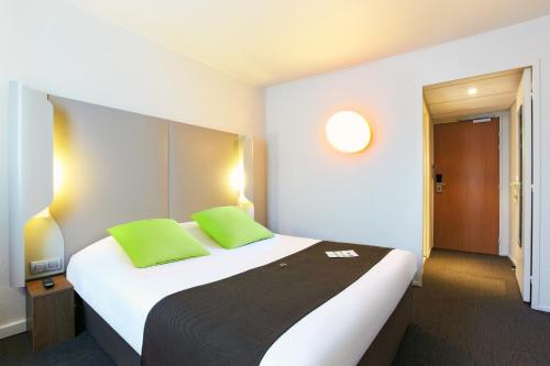 een hotelkamer met een groot bed met groene kussens bij Campanile Paris Ouest - Pont de Suresnes in Suresnes