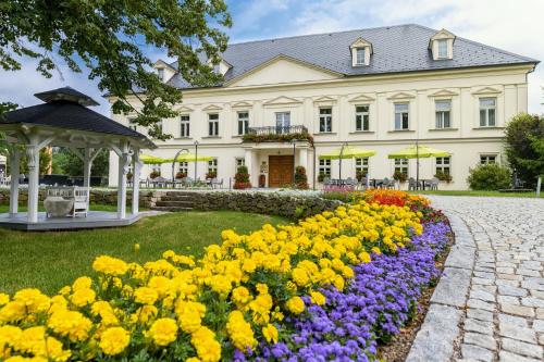 una gran casa blanca con un jardín de flores en Zámeček Petrovice, en Petrovice u Karviné