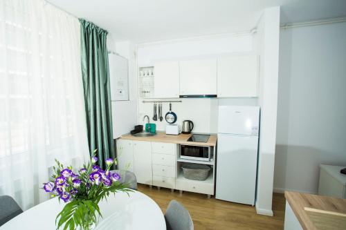 een keuken met witte kasten en een tafel met paarse bloemen bij Residence DP Pipera in Boekarest