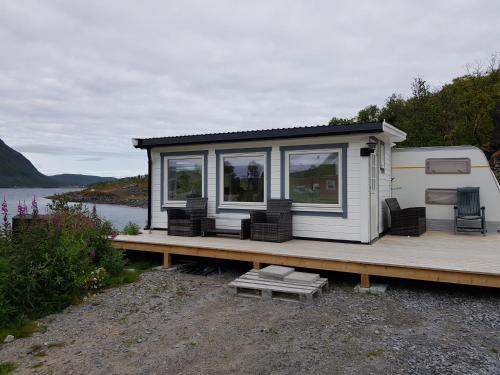 a tiny house sitting on a dock next to a lake at Captains Small House in Hamneide