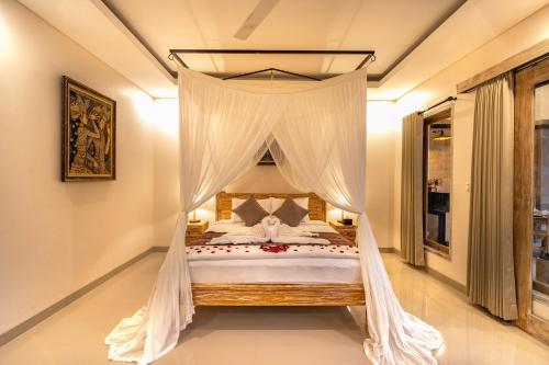 ein Schlafzimmer mit einem Himmelbett mit weißen Vorhängen in der Unterkunft Puri Sedana Ubud Villa in Ubud