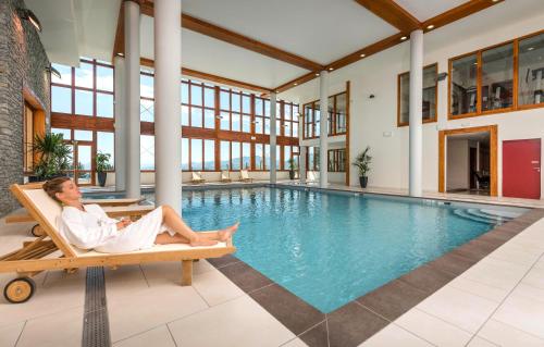 un homme assis dans une chaise à côté d'une piscine dans l'établissement Résidence Prestige Odalys Edenarc, à Arc 1800