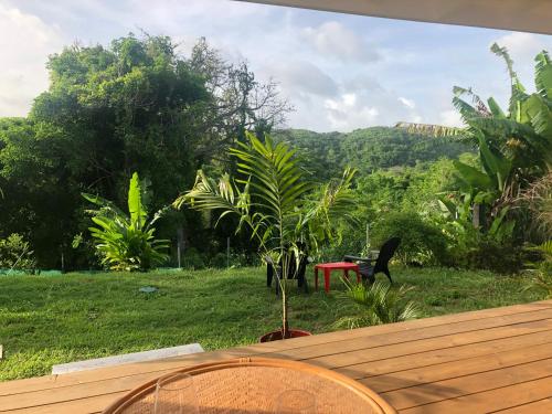 una terraza de madera con una mesa y una planta en Agréable appartement à 2 pas des plages, en Le Gosier