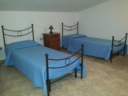 a bedroom with two beds and a wooden dresser at B&B Perdalonga in Ghilarza