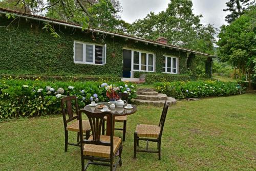 een tafel en stoelen voor een huis bij SaffronStays Nandanvan Estate, Kodaikanal in Kodaikānāl