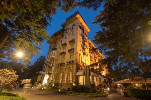 un edificio alto con luces encendidas por la noche en Palace Grand Hotel Varese, en Varese