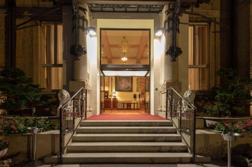 una escalera que conduce a un edificio con alfombra roja en Palace Grand Hotel Varese, en Varese