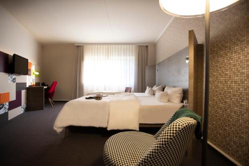 um quarto de hotel com uma cama e uma cadeira em pentahotel Kassel em Kassel