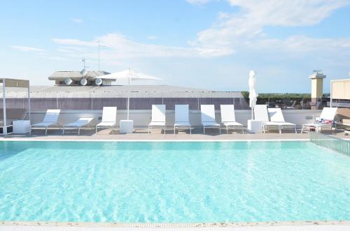 ein Pool auf dem Dach eines Gebäudes mit Stühlen und einem Gebäude in der Unterkunft Hotel Amburgo in Bibione