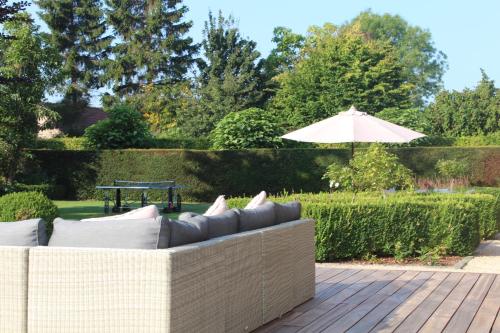 een bank op een patio met een parasol bij Mille Étoiles in Moorsel