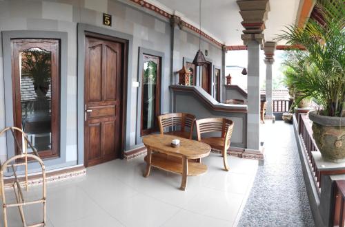 weranda z drewnianym stołem i krzesłami w obiekcie Praety Home Stay w mieście Ubud