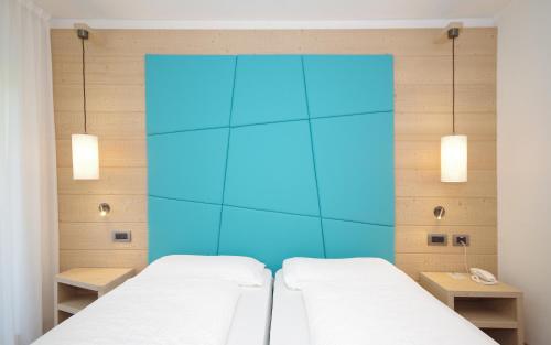 Duas camas num quarto com uma parede azul em Hotel Montana em Madonna di Campiglio