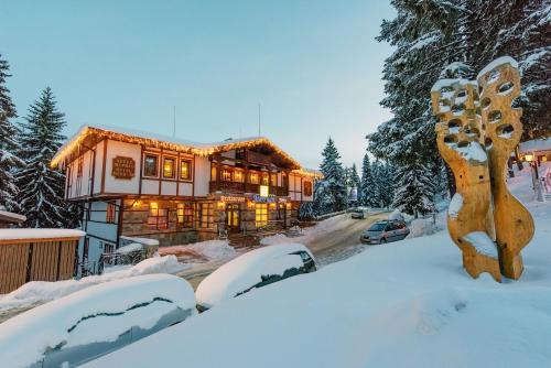 een huis in de sneeuw met besneeuwde daken bij MPM Family Hotel Merryan in Pamporovo