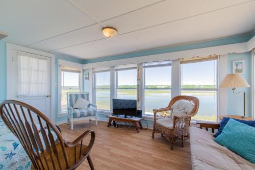 een woonkamer met een bank, stoelen en ramen bij The Eastern Avenue Cottage in Wells Beach