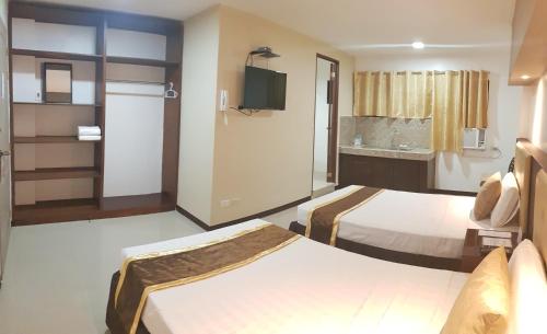 um quarto de hotel com duas camas e uma televisão em North Tourist Inn em Bacolod