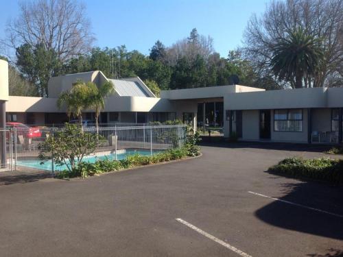 een huis met een auto voor een parkeerplaats bij Durham Court Motor Inn in Tauranga