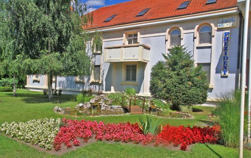 ein Gebäude mit einem Garten mit Blumen davor in der Unterkunft Hotel Prezident in Palić