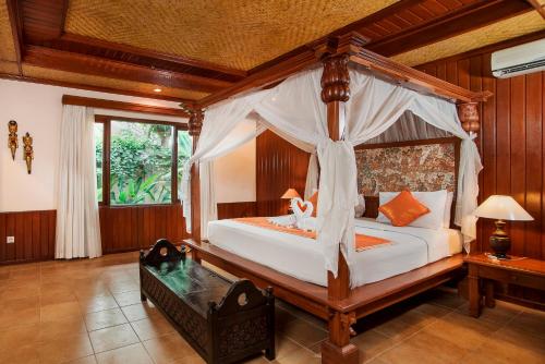 een slaapkamer met een hemelbed en een tafel bij Sri Phala Resort & Villa in Sanur