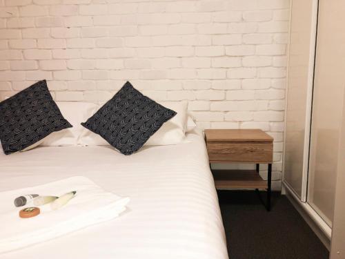 a bed with black and white pillows and a table at Hanbury Lodge in Newcastle