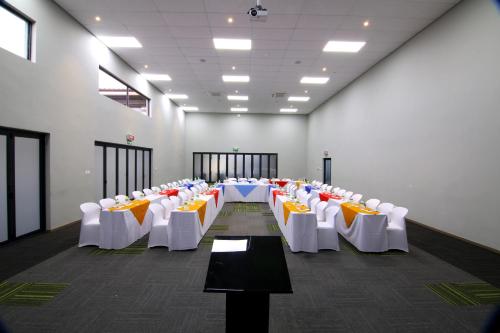 a room with rows of tables and white chairs at Travelodge Kasane in Kasane