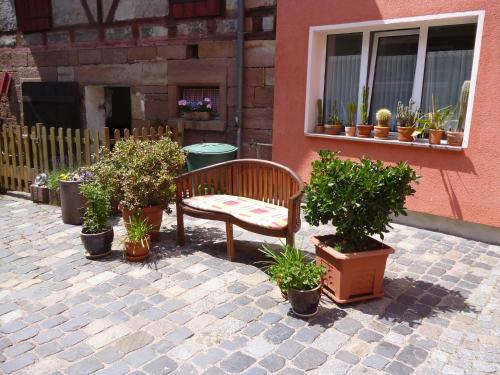 un banc assis devant un bâtiment avec des plantes en pot dans l'établissement Landhauspension Rank, à Bad Berka