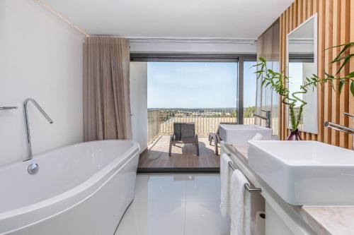 a bathroom with two sinks and a tub with a view at Algarve Race Resort - Hotel in Montes de Cima