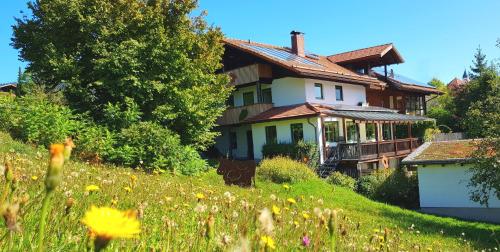 una casa su una collina con un campo di fiori di BIO Appartement Resort a Bodenmais