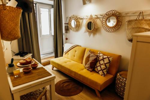 a living room with a yellow couch and mirrors on the wall at Amoreira in Setúbal