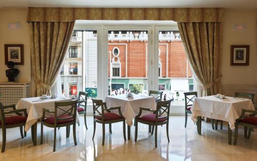 un comedor con mesas y sillas y una gran ventana en Hotel Atlántico, en Madrid