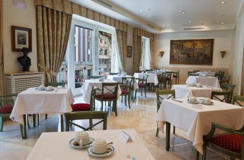 un restaurante con mesas y sillas con mantel blanco en Hotel Atlántico, en Madrid