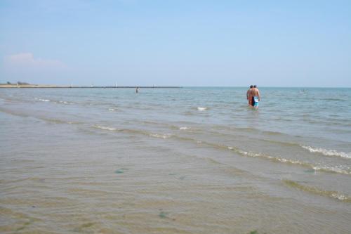 un hombre parado en el agua en la playa en Happy Camp Mobile Homes in Camping Laguna Village, en Caorle