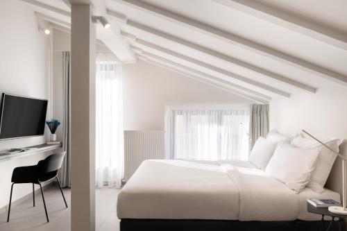 a white bedroom with a bed and a television at Thess Residences in Thessaloniki