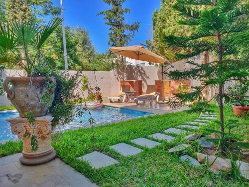 a garden with a pool and an umbrella at Villa Sidi Bou Said in Sidi Bou Saïd