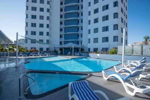 a swimming pool with lounge chairs and a building at Centrepoint Apartments Caloundra in Caloundra