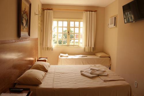 a room with two beds and a window at Pousada Portal do Mar in Cabo Frio