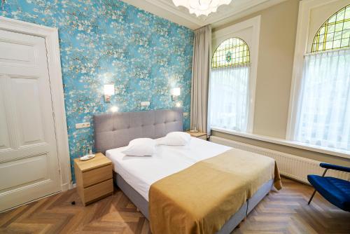 1 dormitorio con 1 cama con papel pintado de flores azul en Hotel Van Walsum, en Róterdam