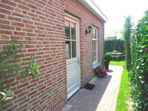 a brick house with a white door and a window at Luxe vakantiewoning Zeeduinsepoort met Sauna in Oostkapelle