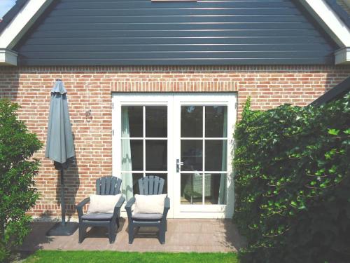 two chairs and an umbrella in front of a house at Luxe vakantiewoning Zeeduinsepoort met Sauna in Oostkapelle