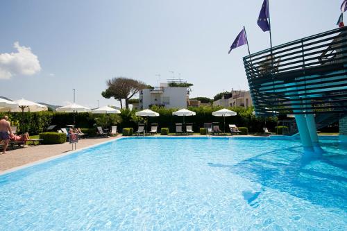 une grande piscine avec des chaises et des parasols dans l'établissement Hotel Poseidon, à Terracine