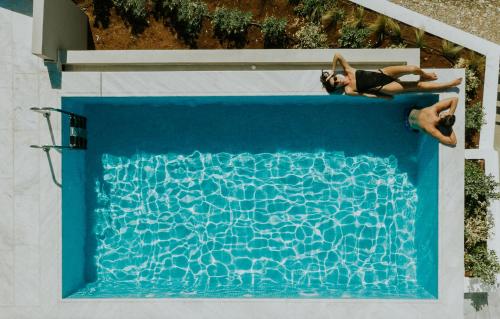 twee personen liggend in een zwembad bij Pefkaki Boutique Hotel Loutraki in Loutraki