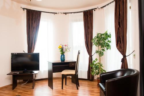 a living room with a television and a desk with a chair at Pensiunea Kenza in Târgu-Mureş