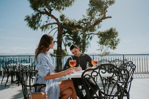 een man en vrouw aan een tafel met wijnglazen bij Pefkaki Boutique Hotel Loutraki in Loutraki