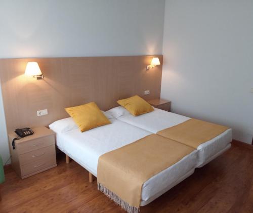 a bedroom with a large bed with two yellow pillows at Hotel San Millán in Santander