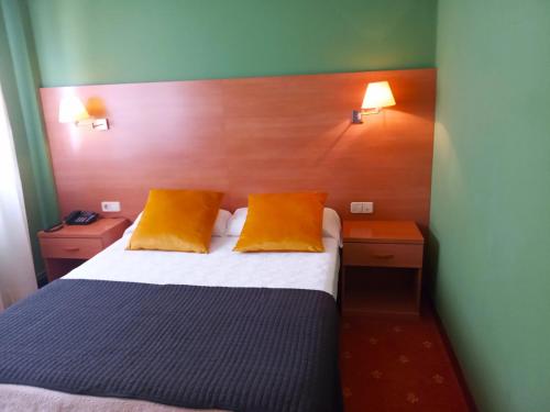 a bedroom with a bed with two orange pillows at Hotel San Millán in Santander